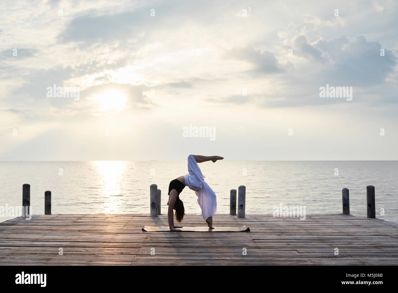Istruttore Yoga fare yoga contro il tramonto e il mare. Kep, Cambogia. Foto Stock