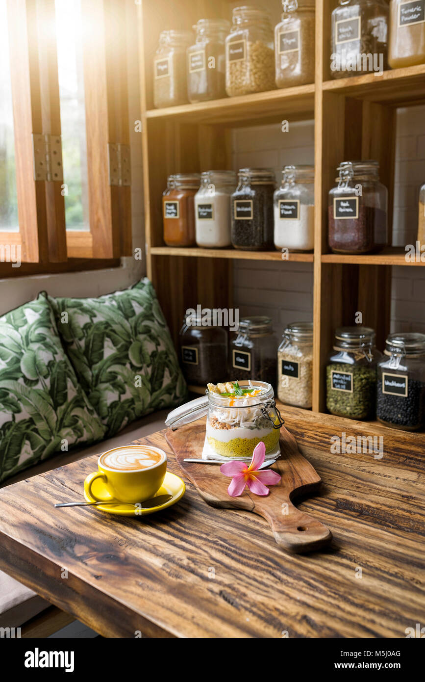Muesli esotico con fiore e la tazza di caffè su di un tavolo di legno Foto Stock
