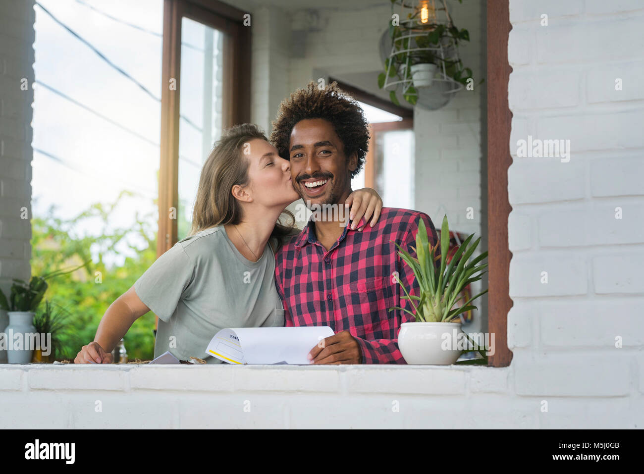Donna baciare il suo fidanzato sulla guancia in cafe Foto Stock