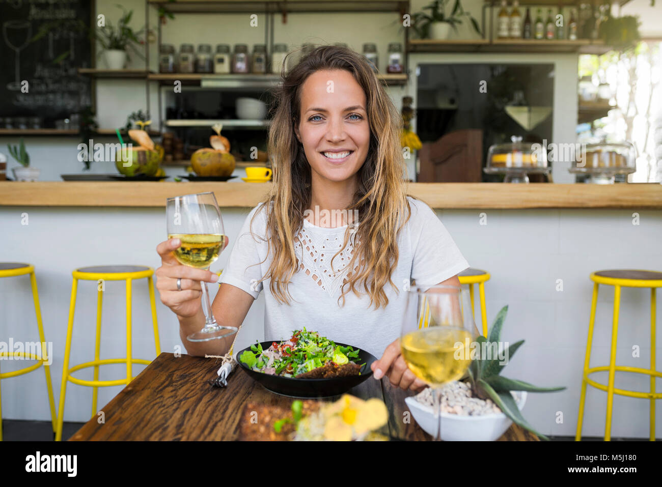 Ritratto di donna sorridente tenendo un bicchiere di vino in un cafe Foto Stock