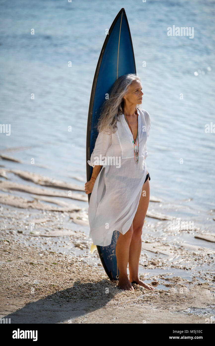 Affettuosa coppia senior con tavole da surf in spiaggia Foto Stock