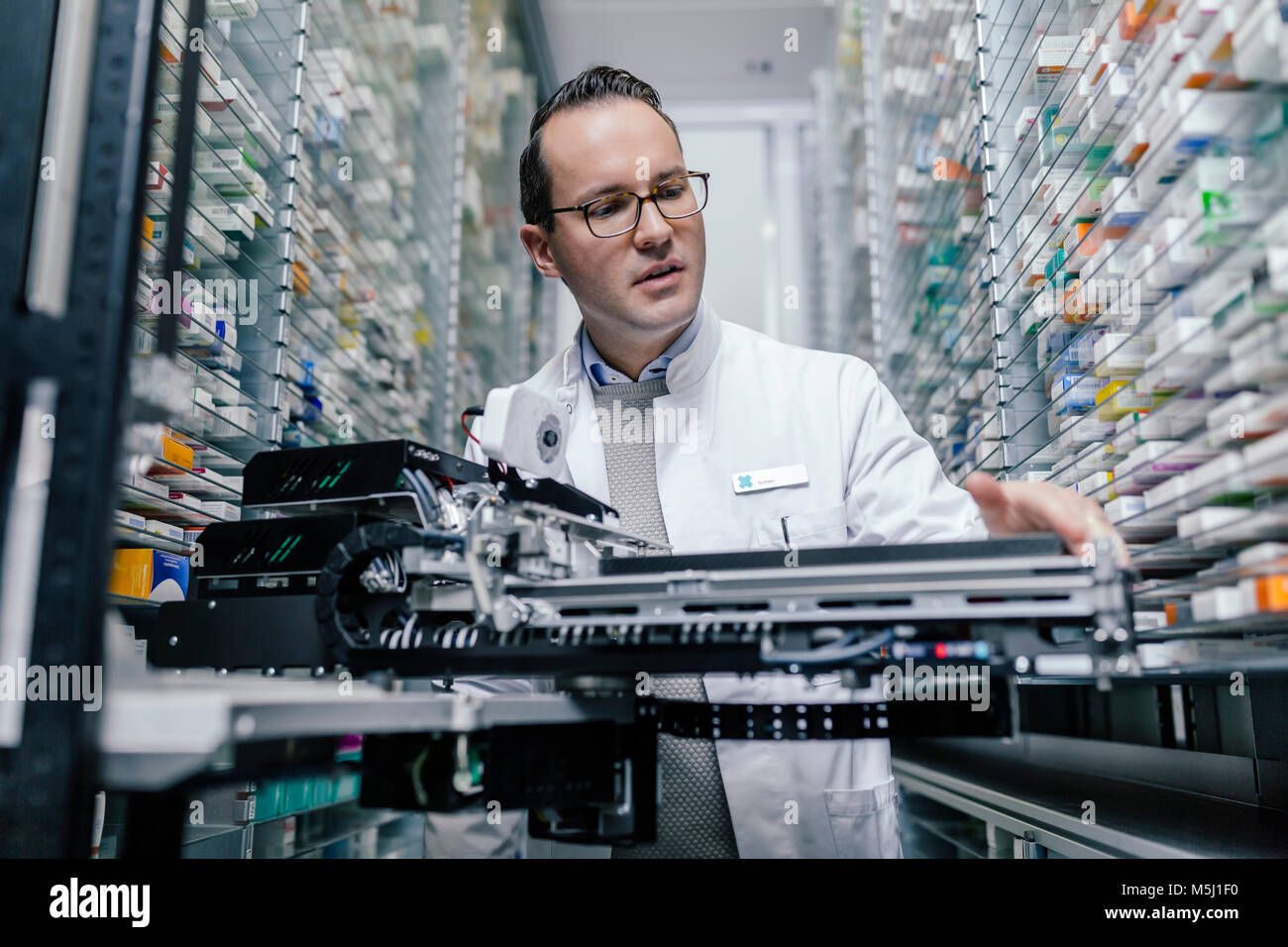 Il farmacista esaminando la messa in funzione la macchina in farmacia Foto Stock