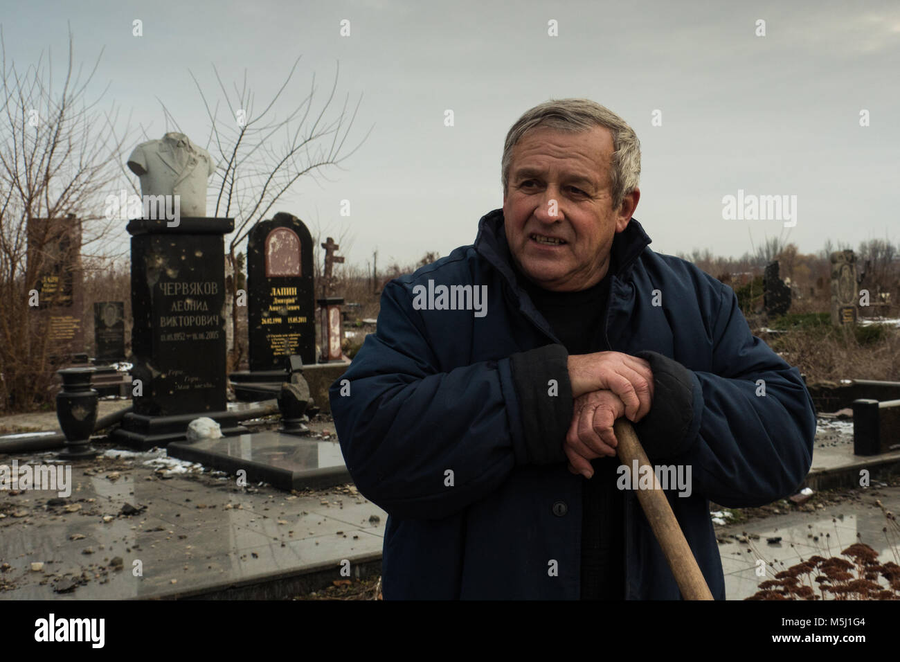 Gravekeeper locale continua il suo lavoro nel cimitero che porta i segni di fuoco pesanti. La questione se egli non ha paura di camminare su un prato pieno di u Foto Stock