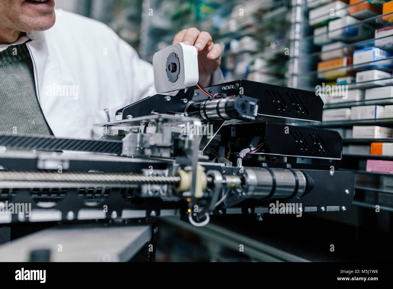 Il farmacista esaminando la messa in funzione la macchina in farmacia Foto Stock