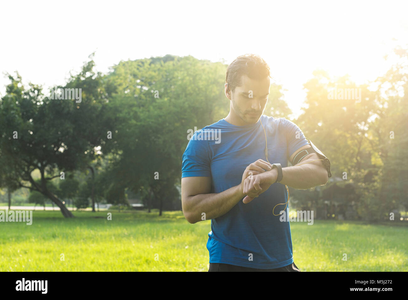 Runner nel parco urbano nel controllo della sua smartwatch Foto Stock