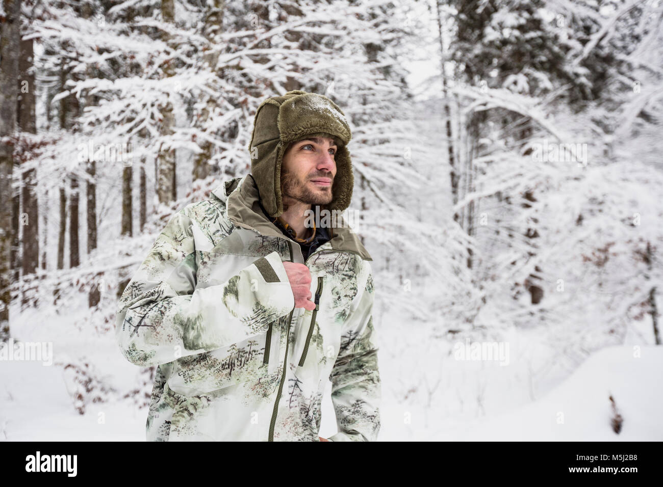 Uomo in camicia di mimetizzazione nella foresta di inverno Foto Stock