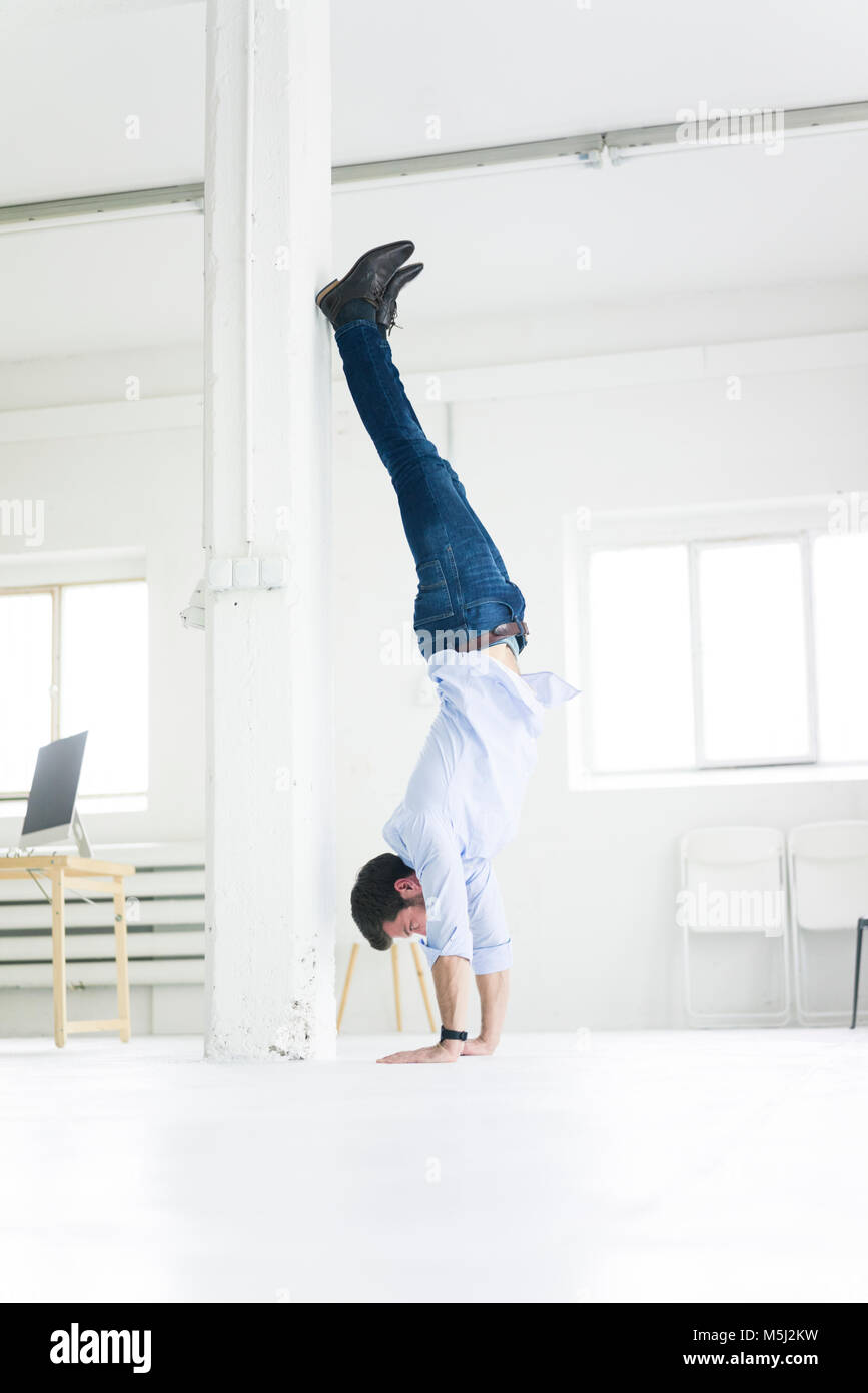 Imprenditore facendo un handstand in office Foto Stock
