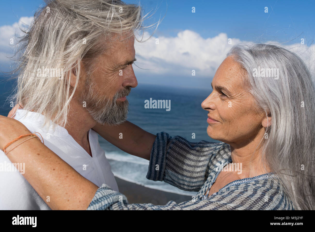 Affettuosa coppia senior cercando in ogni altri occhi di fronte al mare Foto Stock