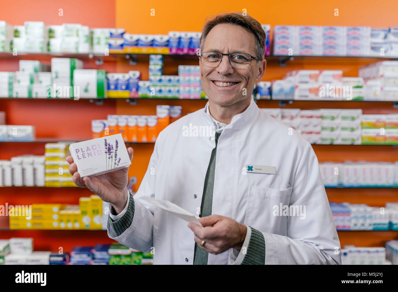 Ritratto di sorridere al farmacista azienda pacchetto compressa e la prescrizione in farmacia Foto Stock