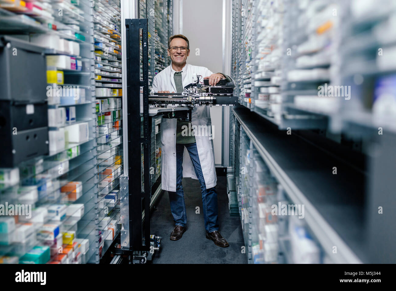 Il farmacista sorridente con la messa in funzione la macchina in farmacia Foto Stock