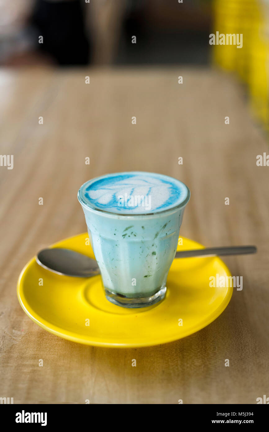 Blue smurf latte con spirulina in vetro di colore giallo sul piattino Foto Stock