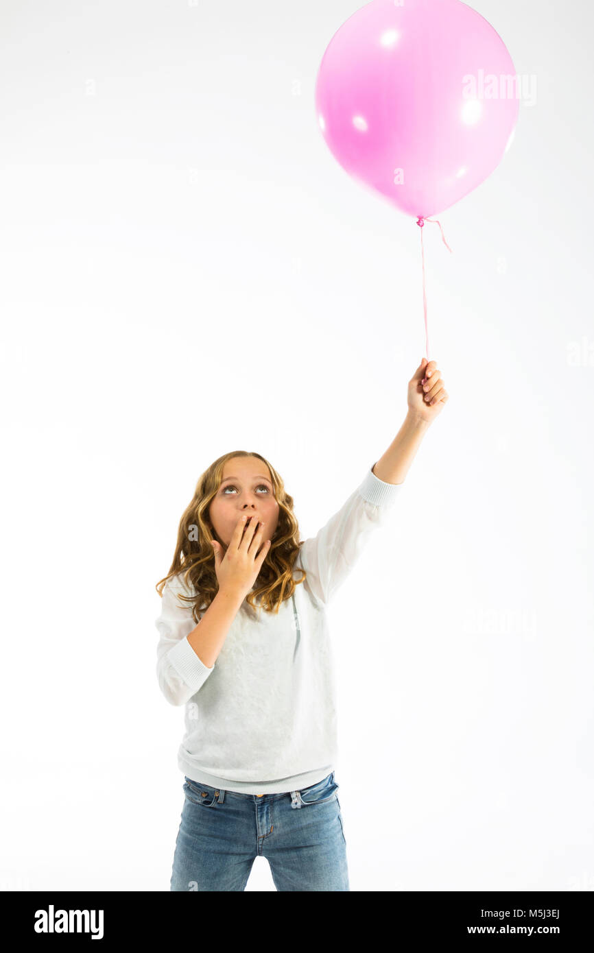 Ragazza che gioca con il palloncino rosa, mano bocca di copertura Foto Stock