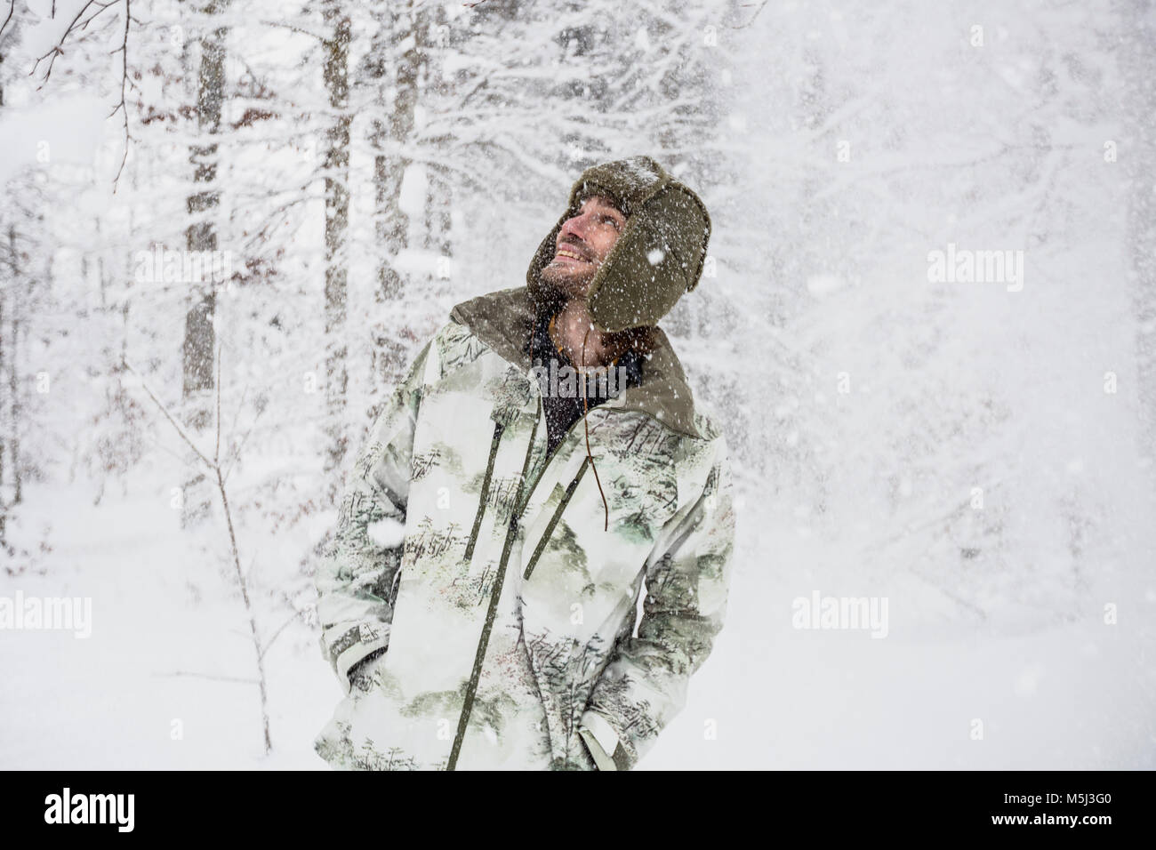 Felice l'Uomo in camicia di mimetizzazione nella foresta di inverno Foto Stock