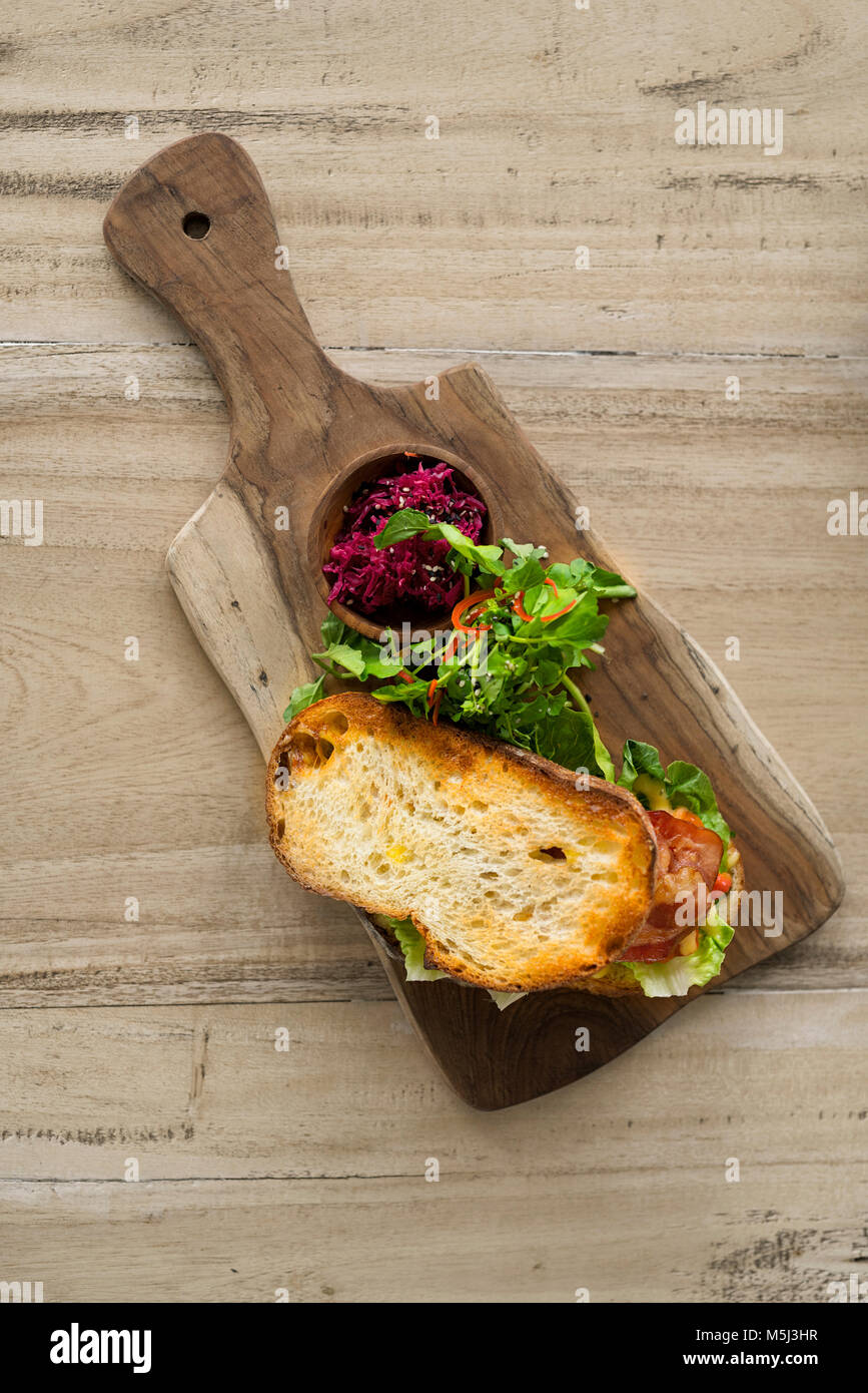 Crostini di pane con insalata verde e prosciutto sul piatto di legno Foto Stock