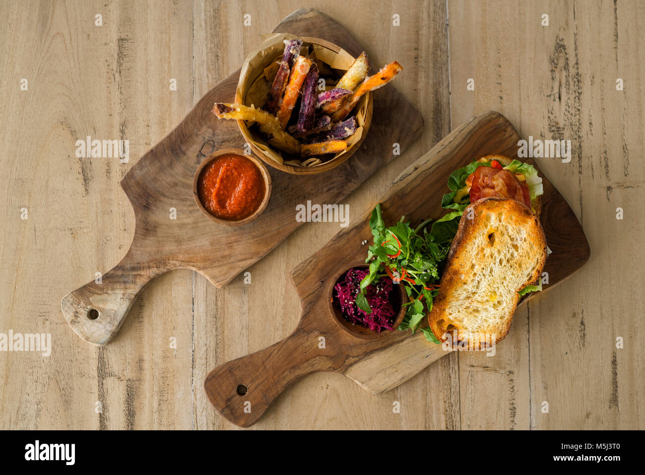 Due piastre in legno con dolci fatti in casa di Patate e patatine, pomodoro dip e di crosta di pane con insalata, prosciutto e barbabietola Foto Stock Due piastre in legno con dolci fatti in casa di Patate e patatine, pomodoro dip e di crosta di pane con insalata, prosciutto e barbabietola Foto Stock
