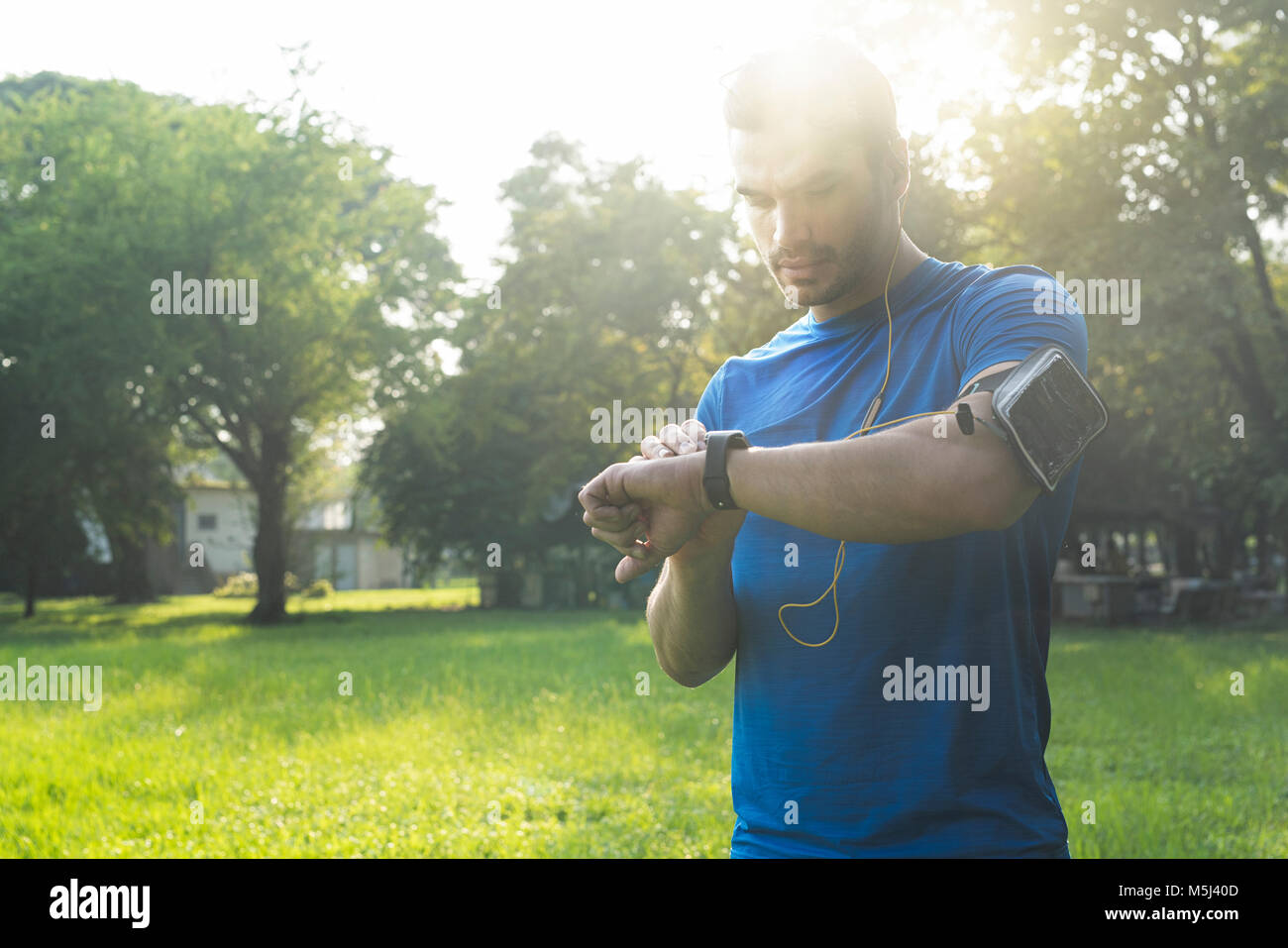Runner nel parco urbano nel controllo della sua smartwatch Foto Stock