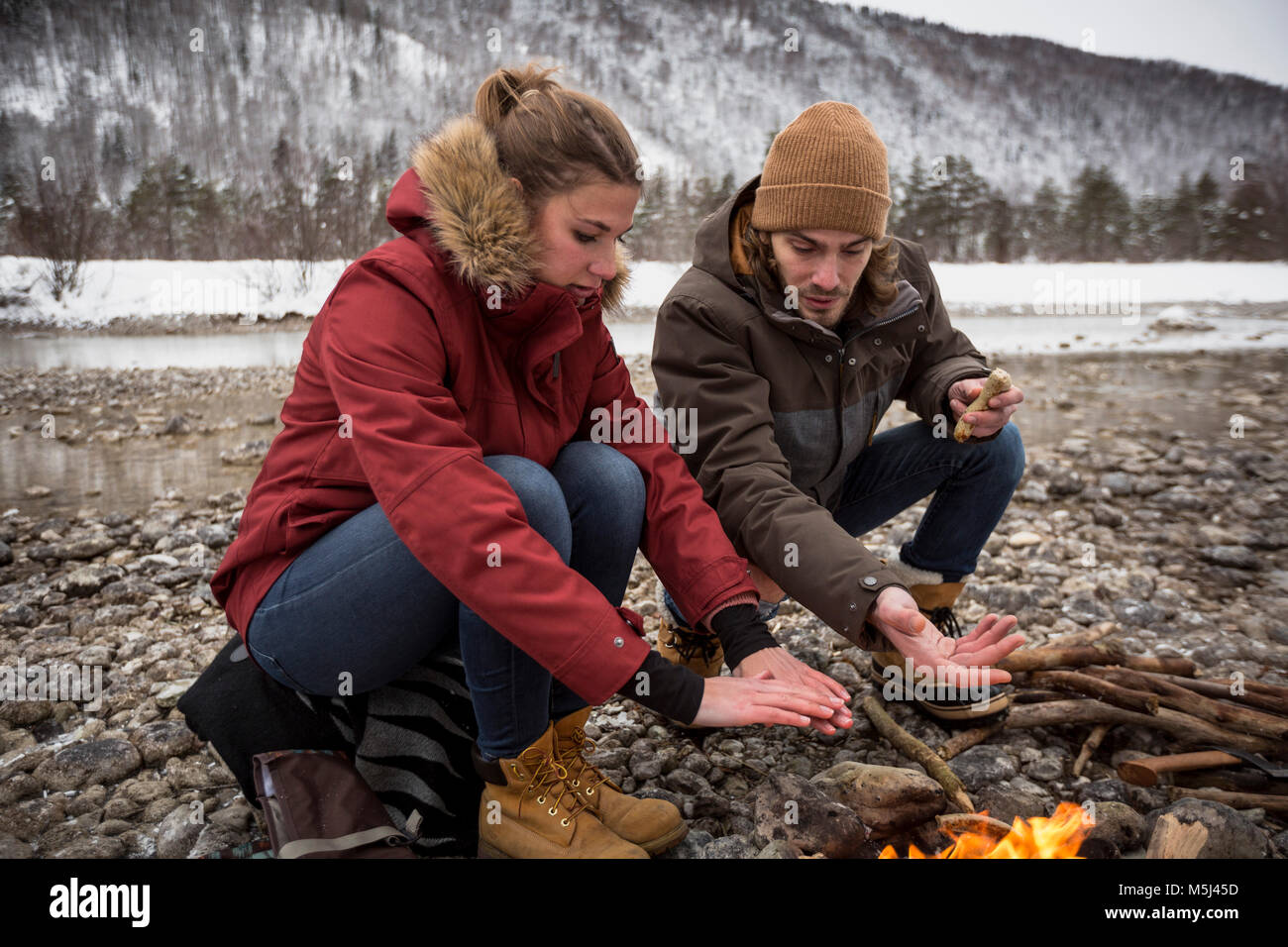 Matura per un viaggio in inverno il riscaldamento le mani al fuoco di campo Foto Stock