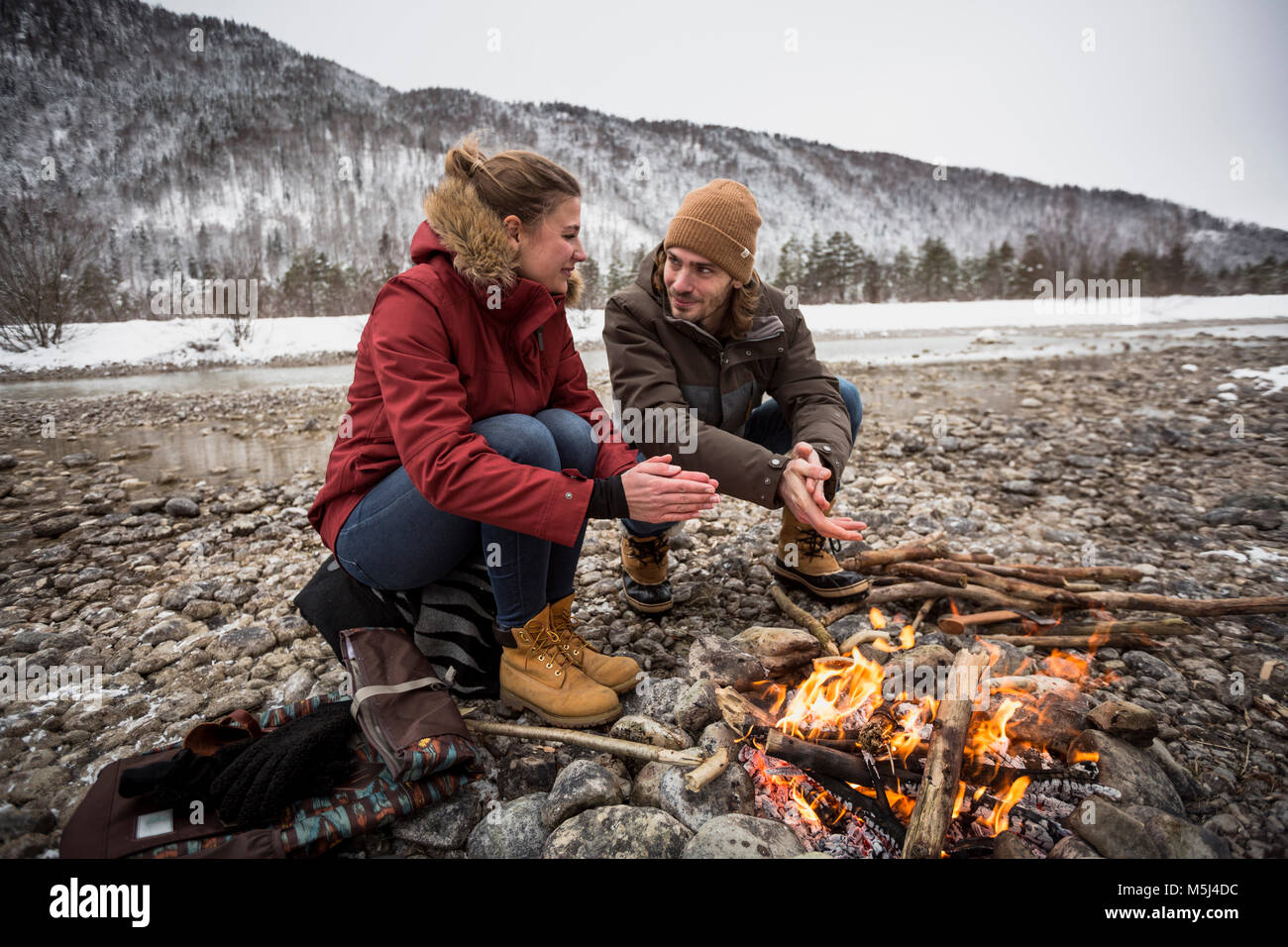 Matura per un viaggio in inverno il riscaldamento le mani al fuoco di campo Foto Stock
