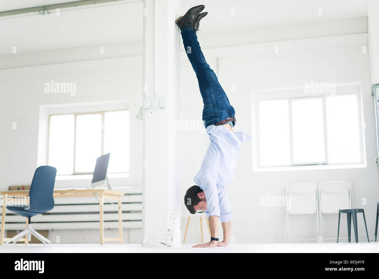 Imprenditore facendo un handstand in office Foto Stock