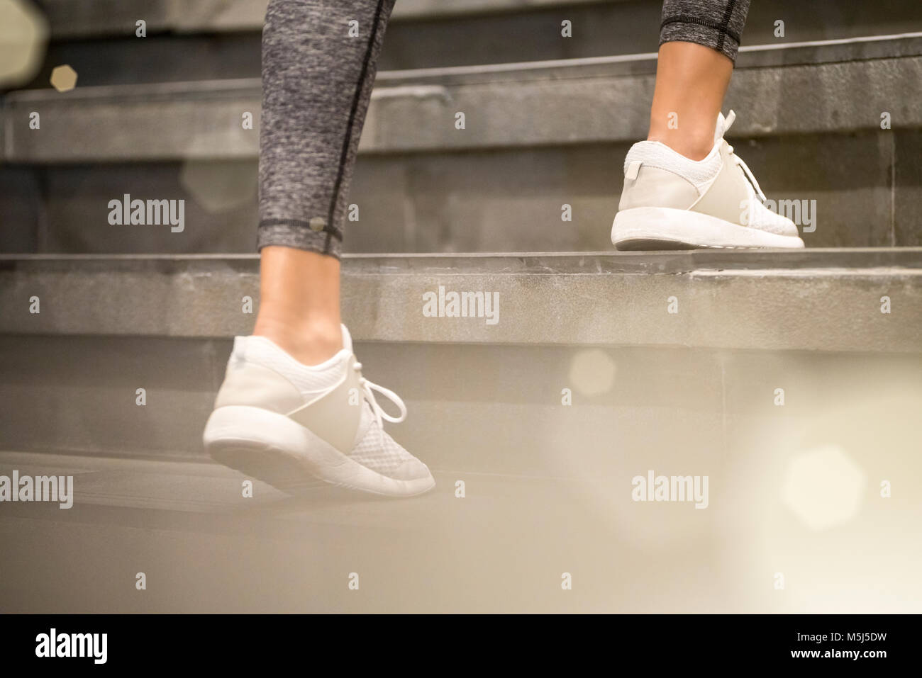 In prossimità delle gambe femmina con il bianco sport sneakers in esecuzione su per le scale Foto Stock
