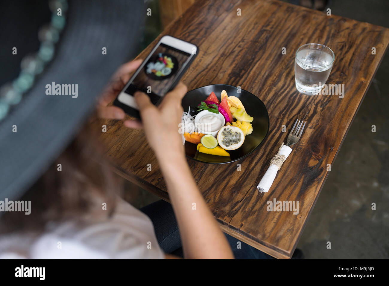 Donna di scattare una foto di cibo su una piastra con lo smartphone Foto Stock