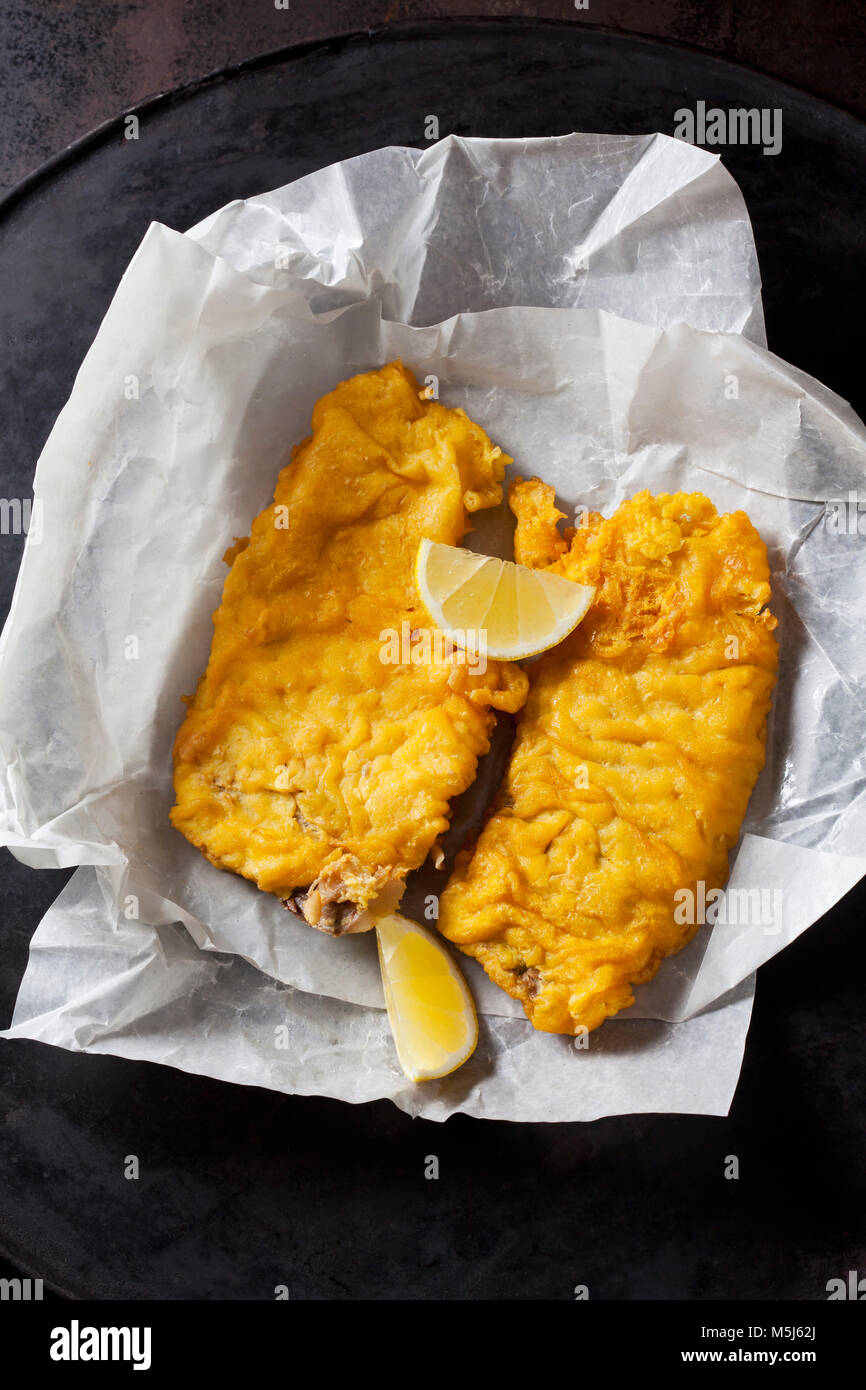 Merluzzi carbonari fritto filet e le fette di limone sulla carta oleata Foto Stock