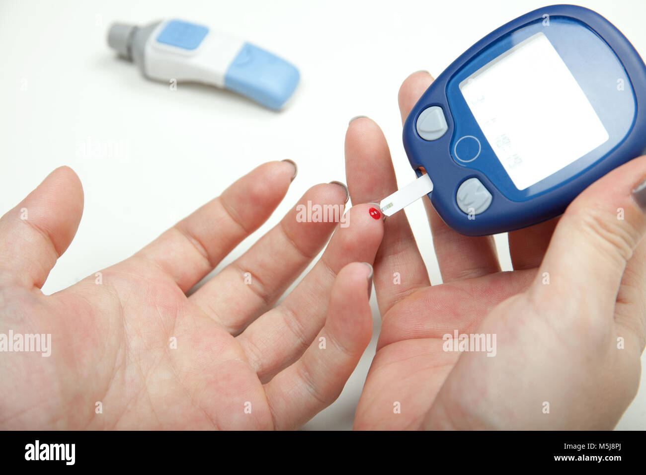 Donna mani test ad alto livello di zucchero nel sangue con il glucometro Foto Stock