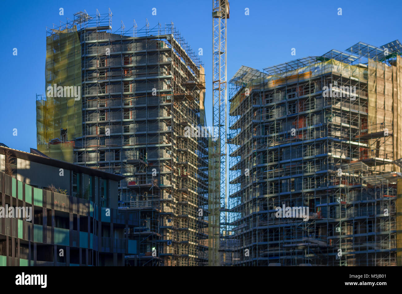 Sun sulle facciate degli edifici in costruzione coperta con i ponteggi Foto Stock
