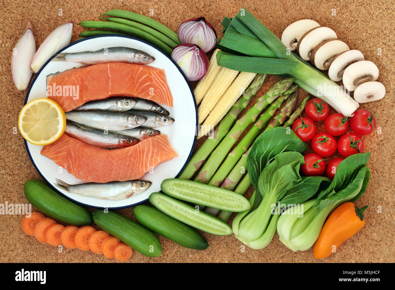 Della salute alimentare per il concetto di fitness con pesce fresco e verdure su sfondo di sughero. Cibo sano e alto contenuto di omega 3, antiossidanti antocianine e vitamine. Foto Stock