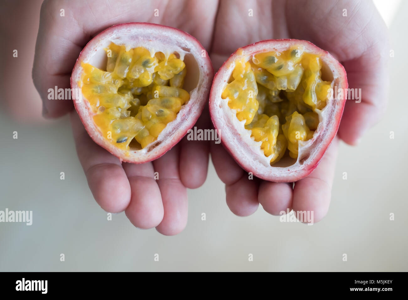 Mano di donna caucasica holding succoso frutto della passione Foto Stock