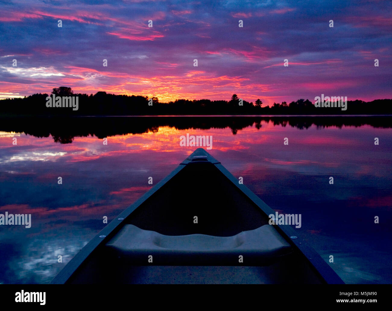 Una canoa punti verso il tramonto su un lago del Minnesota. Stati Uniti d'America. Foto Stock