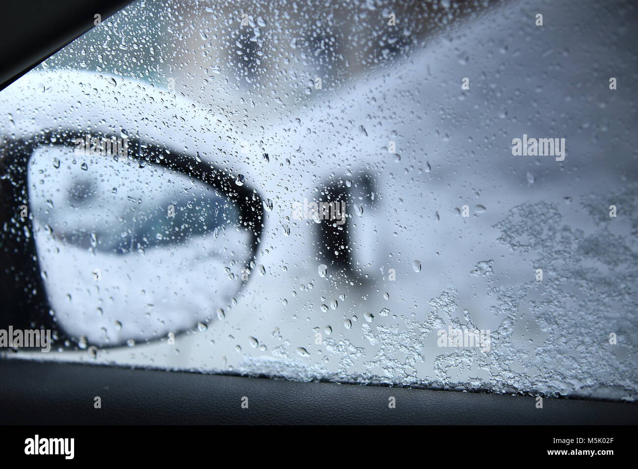 Gocce di acqua su auto window close-up. La guida pericolosa in caso di cattive condizioni atmosferiche. Tempo piovoso fuori dall'auto. Foto Stock