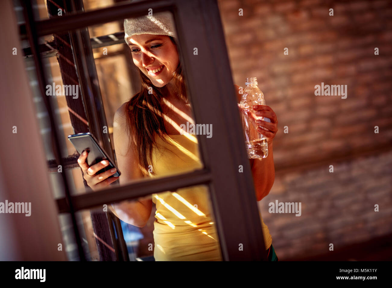 Urbano sorridente ragazza con un telefono cellulare e acqua Foto Stock