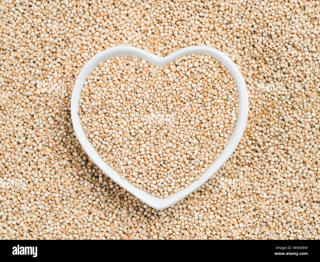 La quinoa in a forma di cuore sulla tazza di quinoa sfondo. Senza glutine di grano antico per una sana dieta. Io amo la quinoa concetto. Copia dello spazio. Foto Stock