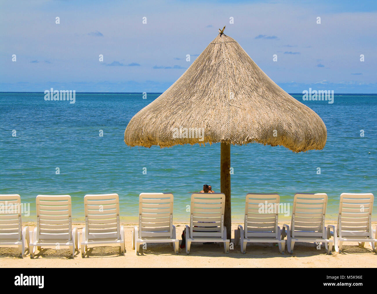Lettini e ombrellone in spiaggia di Baia Turchese Resort, Roatan Island, Bay Islands in Honduras Caraibi Foto Stock