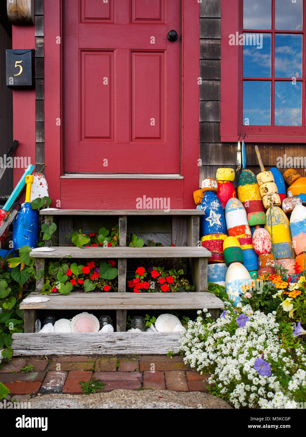 Porta Rossa porta d ingresso con colorati boe, fiori, conchiglie di mare e il cloud riflessioni nella finestra al porto di Rockport MA. Foto Stock