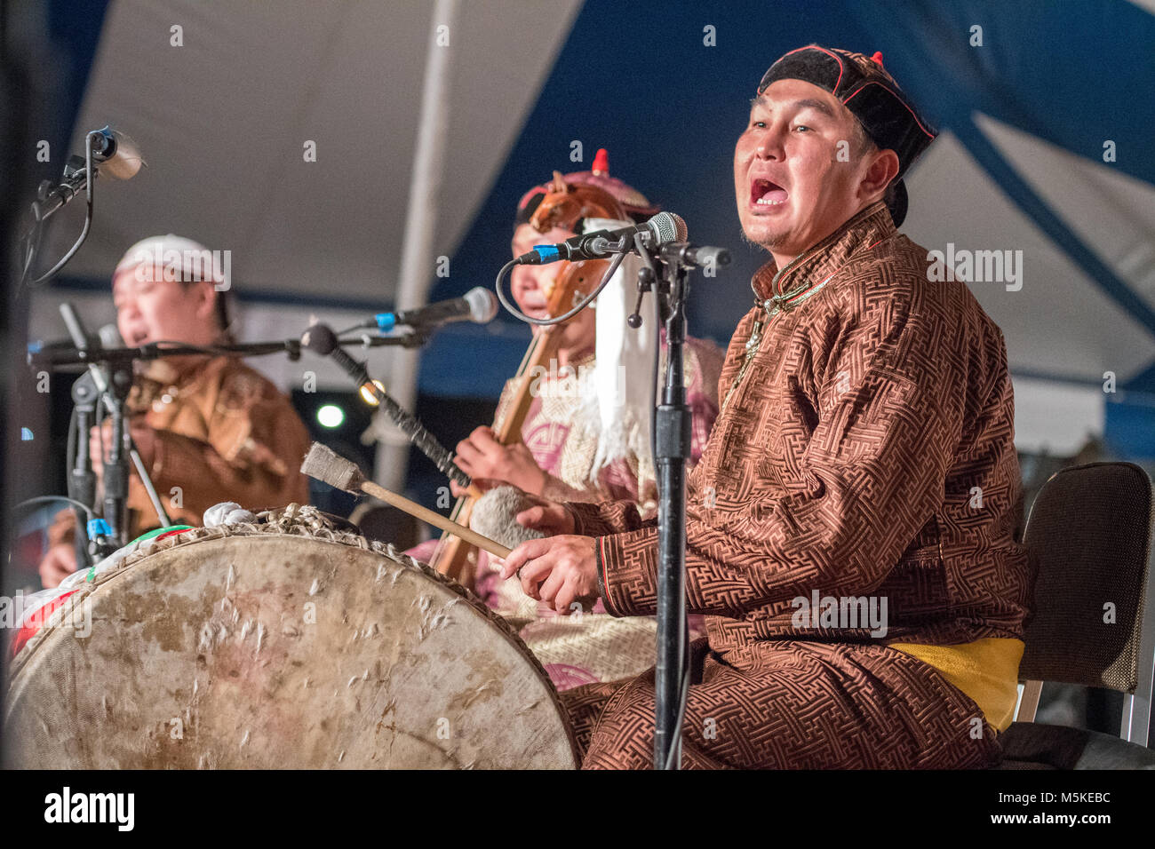 Gli stati da Alash gruppo musicale Tuvan preformatura della gola di cantare e suonare il tamburo sul palcoscenico nazionale vita Folk Festival, Greensboro, Nord Carolina. Foto Stock