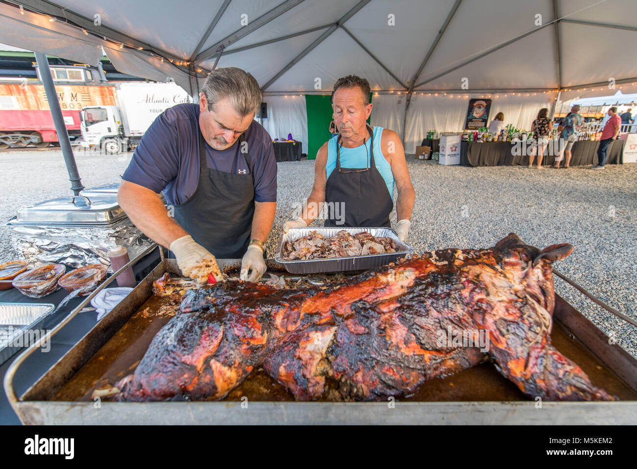 Due uomo di mezza età il taglio di carne fuori di arrosto di maiale nella preparazione all evento, Baltimore, Maryland. Foto Stock