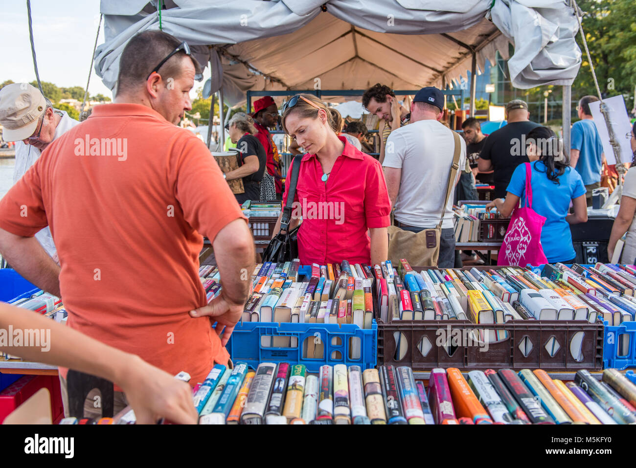 Gruppo di individui navigare attraverso le casse contiene numerosi libri per la vendita, Baltimore, Maryland. Foto Stock