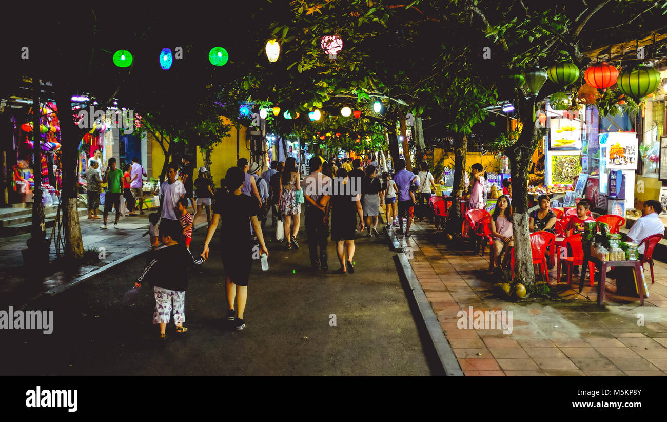 I turisti a piedi attraverso Hoi An Old Town di notte con tutto il colorato lanterne accese fino in Vietnam Foto Stock