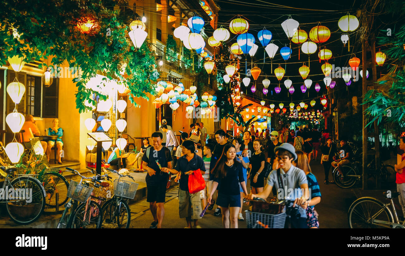 I turisti a piedi attraverso Hoi An Old Town di notte con tutto il colorato lanterne accese fino in Vietnam Foto Stock
