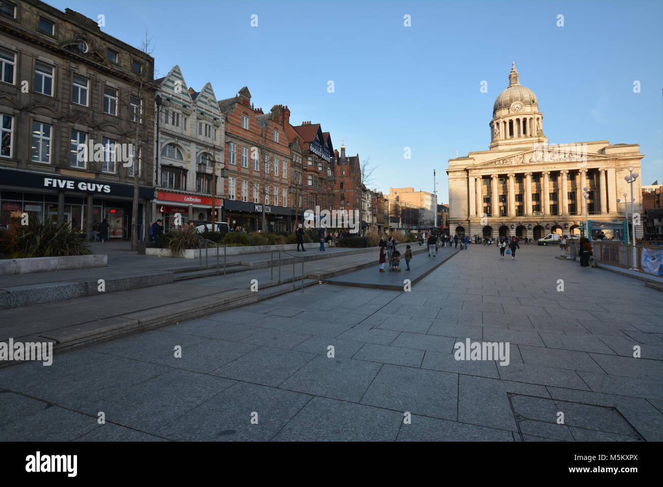 Nottingham, Inghilterra - Febbraio 24, 2018: turisti shopping presso i negozi sulla Piazza del Mercato Vecchio con la Casa del Consiglio durante la primavera. Foto Stock