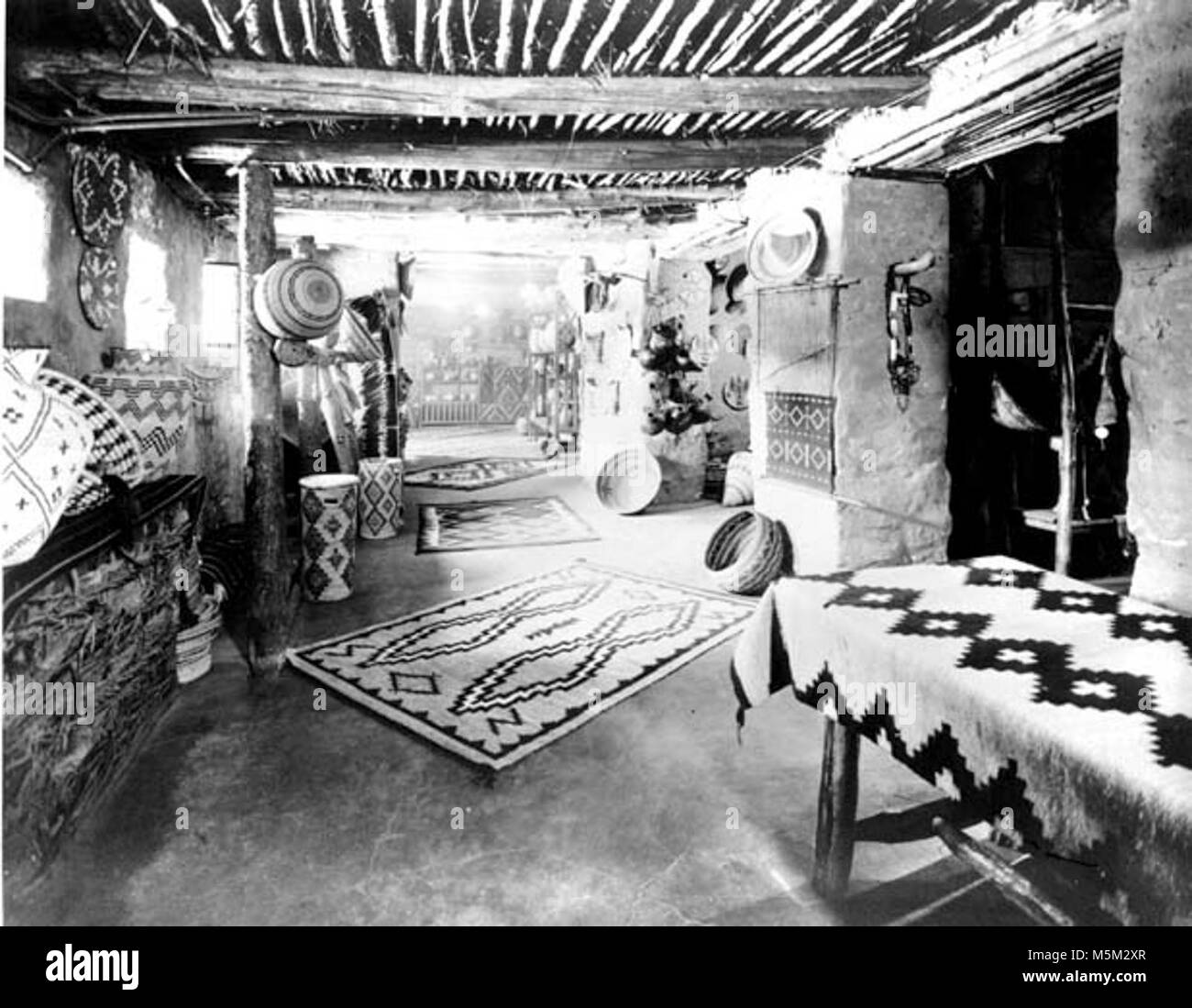 Grand Canyon Hopi storico interno di una casa c . Piano terra sala vendita in hopi house. Visualizzazione delle ceste e tappeti navajo. Circa 1905. Foto Stock