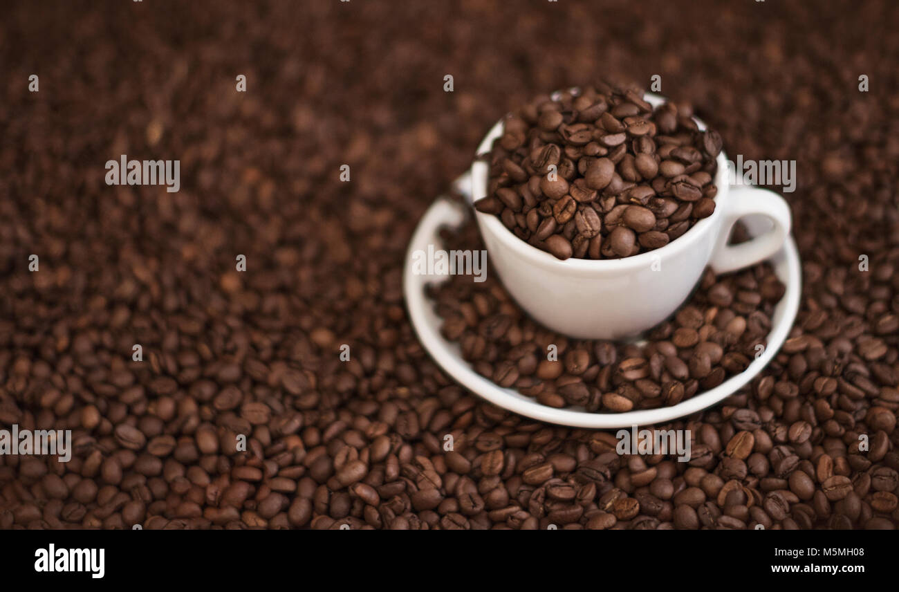 Tazza di caffè e i chicchi di caffè sul tavolo di legno. I chicchi di caffè vicino. Foto Stock