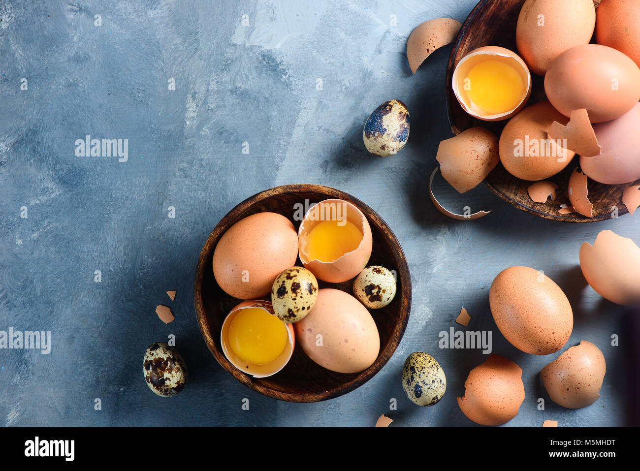 Per la cottura di uova crude sfondo. Quaglia e marrone uova di pollo su un piatto di legno. Moderno concetto di Pasqua con copia spazio. Foto Stock