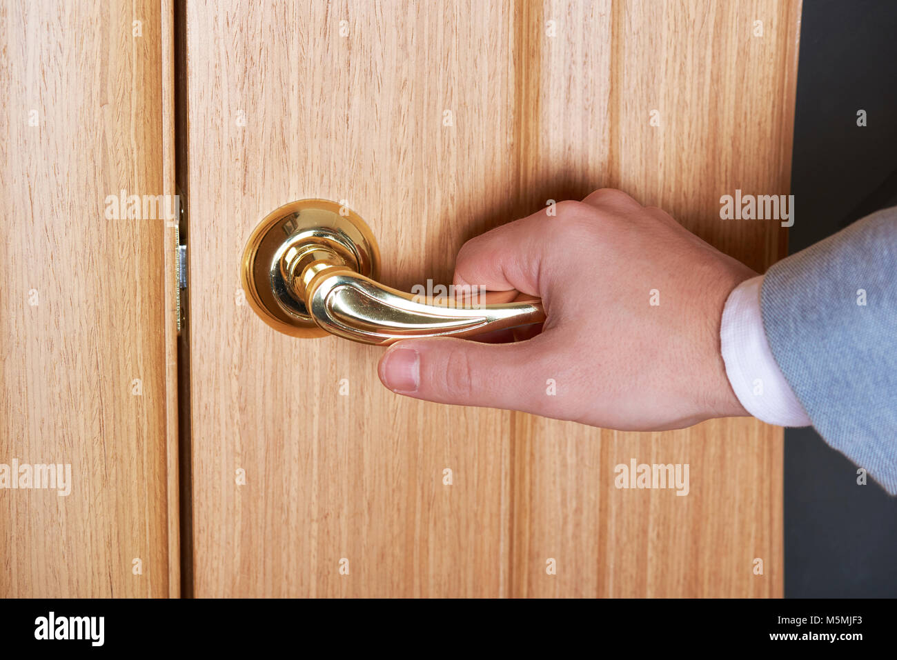 Close-up della mano sulla maniglia della porta. Golden maniglia sulla porta di legno Foto Stock