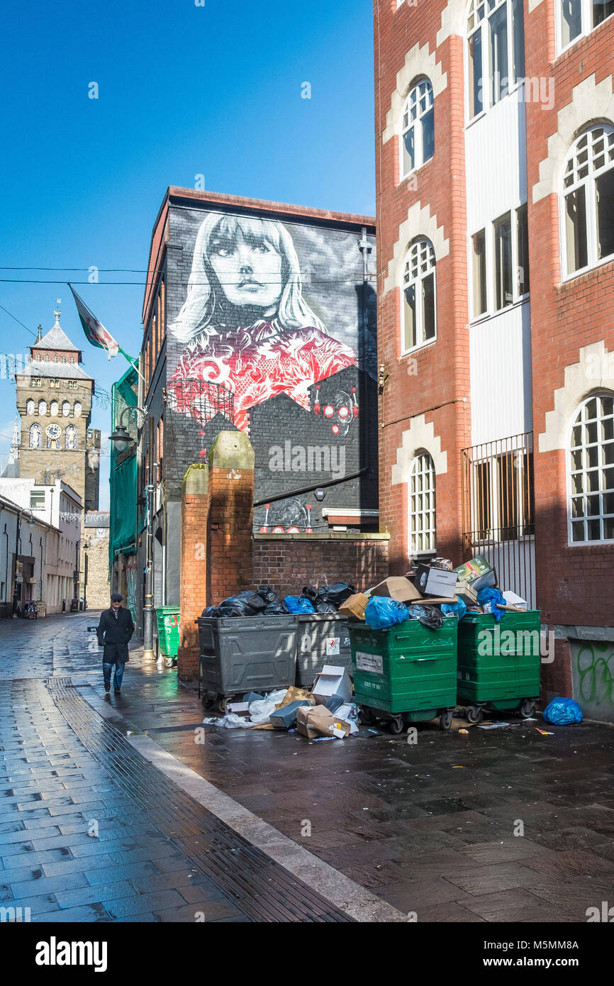 Traboccante di rifiuti raccoglitori di immondizia in una strada laterale nel centro di Cardiff. Foto Stock