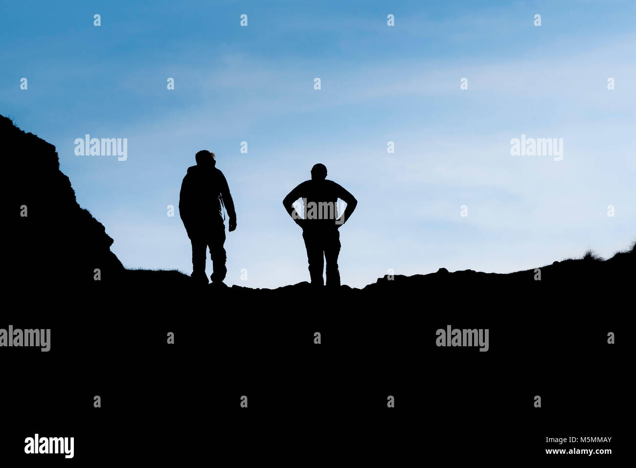 La silhouette di due escursionisti sulla costa sud ovest percorso in Cornovaglia. Foto Stock
