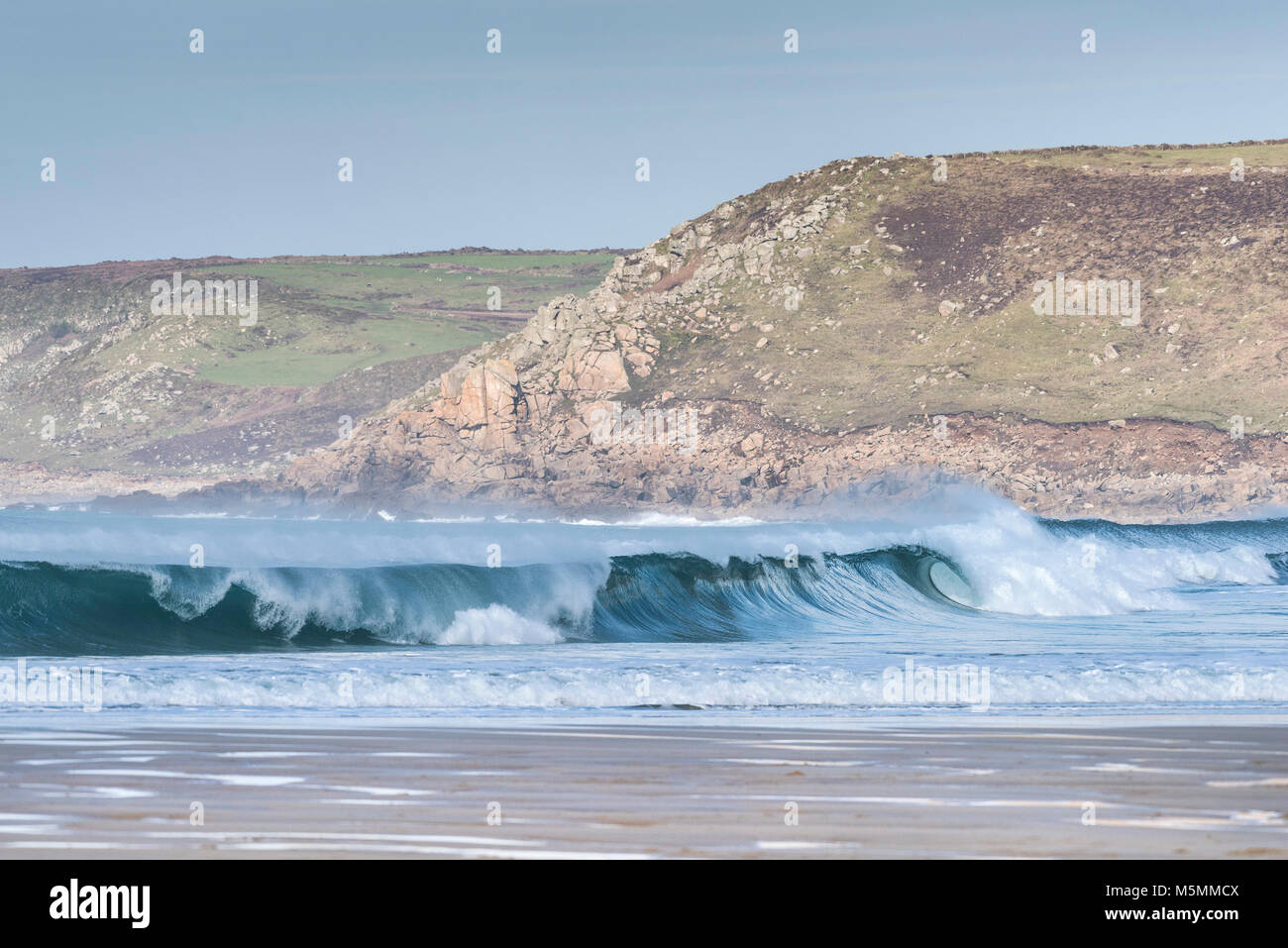 Un'onda rompe in Sennen Cove in Cornovaglia. Foto Stock