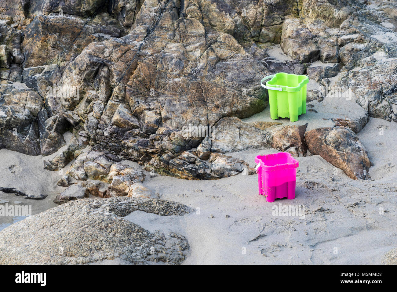 Due coloratissimi secchielli in plastica lasciato sulla spiaggia di Sennen Cove in Cornovaglia. Foto Stock